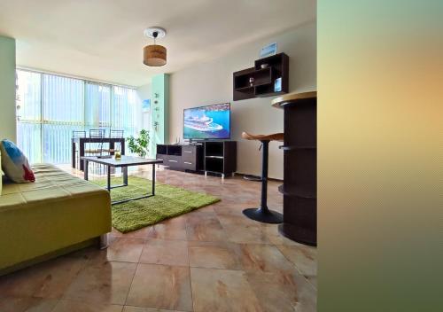 a living room with a couch and a table and a tv at Апартамент FLAME in Sunny Beach