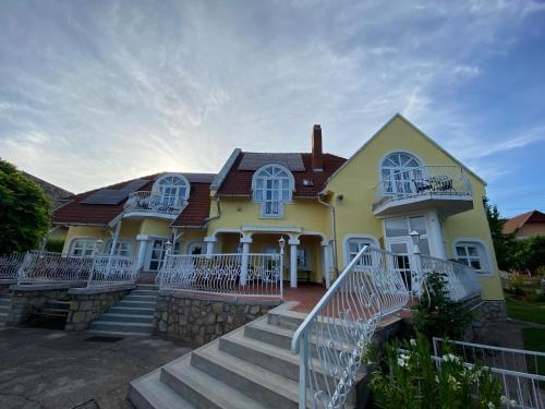 ein gelbes Haus mit weißen Fenstern und Treppen in der Unterkunft Vázsonyi vendégház in Balatonfüred