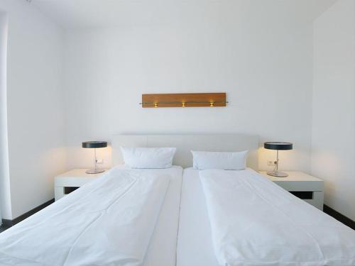 a white bed with two tables and two lamps at Luxury Golf Apartment Bad Bellingen 5-9 in Bad Bellingen