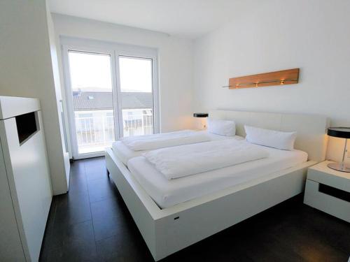 a white bedroom with a large bed and a window at Luxury Golf Apartment Bad Bellingen 5-9 in Bad Bellingen