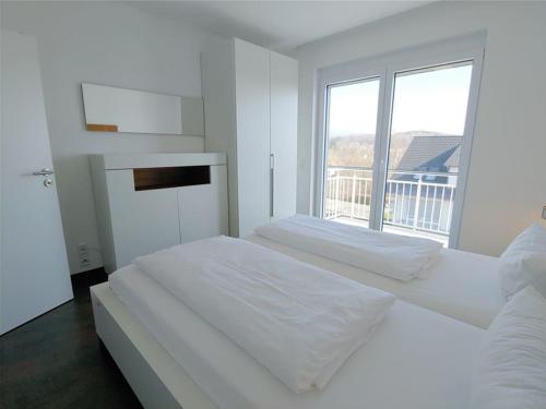a white bedroom with a large bed and a window at Golf & Wellness Suite Bad Bellingen Apartment 5-9 in Bad Bellingen
