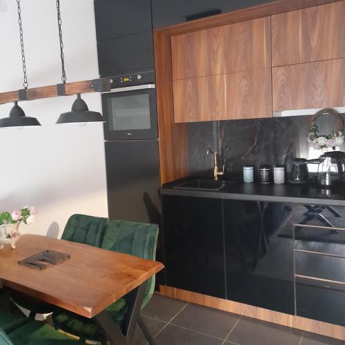 a kitchen with a wooden table and a black counter at Vrnjačka Promenada - Pešačka zona - Baby friendly in Vrnjačka Banja