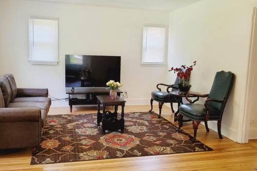 a living room with a couch and chairs and a television at Greensboro Downtown House in Greensboro