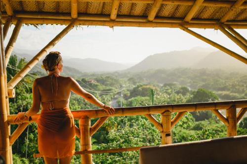 a woman standing on a balcony looking out at the mountains at The Journey Hostel in Los Naranjos