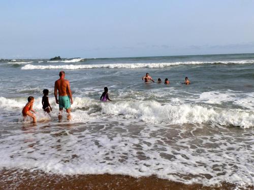 a group of people playing in the water at the beach at Ankobra Beach Resort in Axim