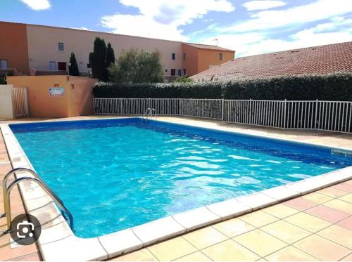 une grande piscine bleue devant un immeuble dans l'établissement Pavillon 20m de la plage des ayguades, à Gruissan