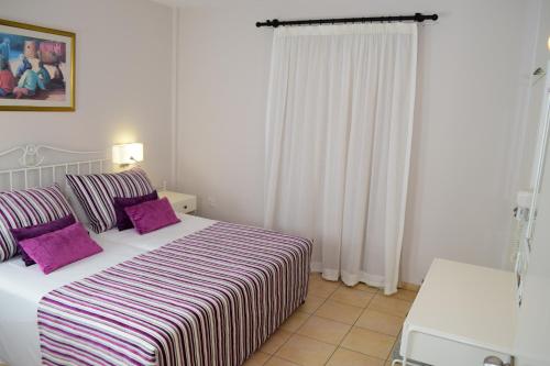 a bedroom with a large bed with purple pillows at Aktea Beach Village in Ayia Napa