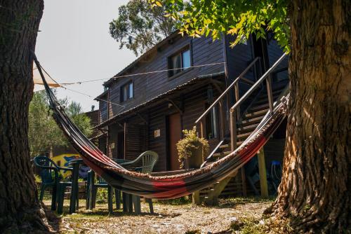 a hammock in front of a log cabin at Cabañas PATALSUELO in Barra de Valizas