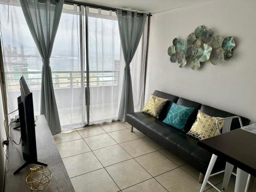 a living room with a couch and a balcony at Departamento NEO IQUIQUE VISTA AL MAR 3 in Iquique