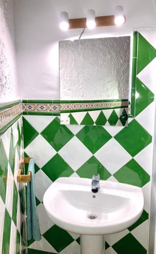 a green and white bathroom with a sink and a mirror at Casa rural Almazara in Letur