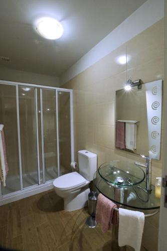 a bathroom with a toilet and a glass sink at Casa férias, piscina, Ponte de Lima in Ponte de Lima
