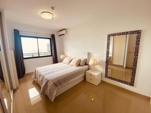 Schlafzimmer mit einem Bett mit einem Spiegel und einem Fenster in der Unterkunft Gold Sunset in Adeje