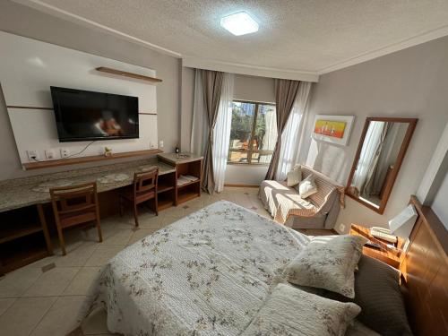 een slaapkamer met een bed, een bureau en een televisie bij Apartamento executivo in Florianópolis