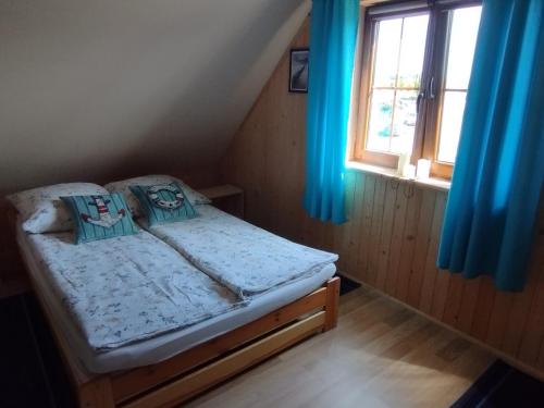 ŁebczにあるWakacyjny Łebczの青いカーテンが備わる客室の小さなベッド1台分です。