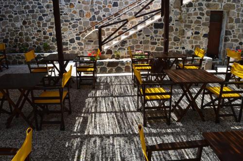 an empty restaurant with wooden tables and yellow chairs at Romantzo in Mandrákion