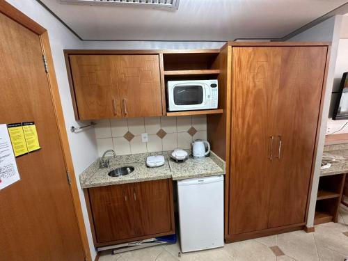 a small kitchen with a sink and a microwave at Apartamento executivo in Florianópolis