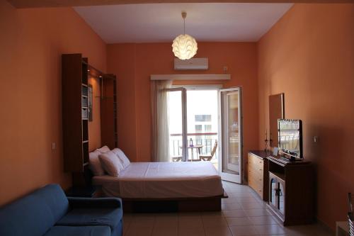 una camera con letto, divano e TV di Captain's Lodge a Ermoupoli