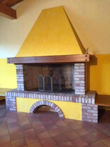 a brick fireplace in a room with a yellow roof at Foresto Case Vacanza in Volta Mantovana