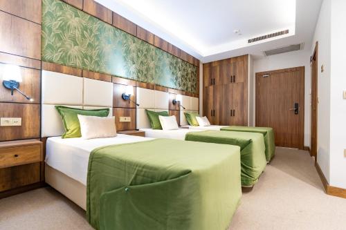 two beds in a room with green sheets at Mardy Suit Hotel in Istanbul