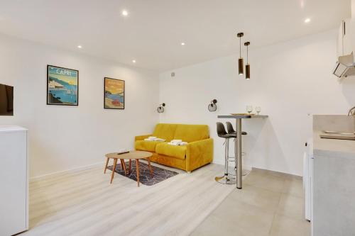 a living room with a yellow couch and a table at Fully renovated studio Buttes-Chaumont in Paris