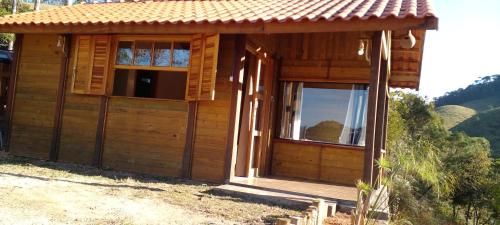a small wooden cabin with a porch and two windows at Chale brilho do sol in Visconde De Maua