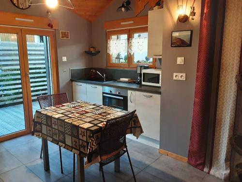 une cuisine avec une table avec des chaises et un micro-ondes dans l'établissement Chalet la Petite Perle, à Gérardmer