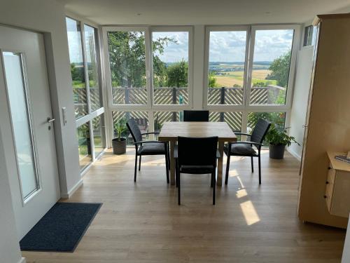 a dining room with a table and chairs and windows at Ferienwohnung Bröder in Emmelshausen