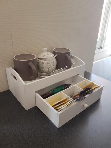 a white cabinet with two cups and utensils in it at Artbnb in Lézat-sur-Lèze