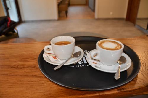 two cups of coffee on a black plate on a table at Die Pension Galle in Arnoldstein
