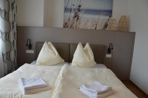 a bed with white pillows and towels on it at Die Pension Galle in Arnoldstein