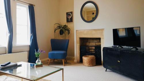 sala de estar con silla azul y TV en Willoughby Apartment, en Bath