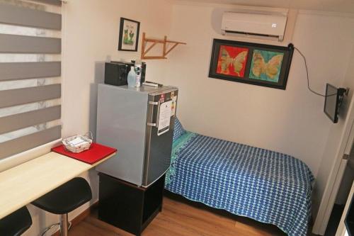 Habitación con escritorio, nevera y cama. en Departamentos comodos y hermosos full equipados con baño y cocina privados en Santiago