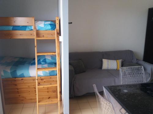 Cette chambre dispose de lits superposés et d'un canapé. dans l'établissement STUDIO LES PIEDS DANS L'EAU, à Canet
