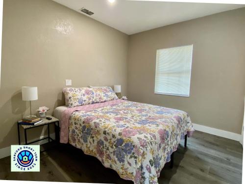 a bedroom with a bed with a floral bedspread and a window at The Cherry Blossom in Sanford