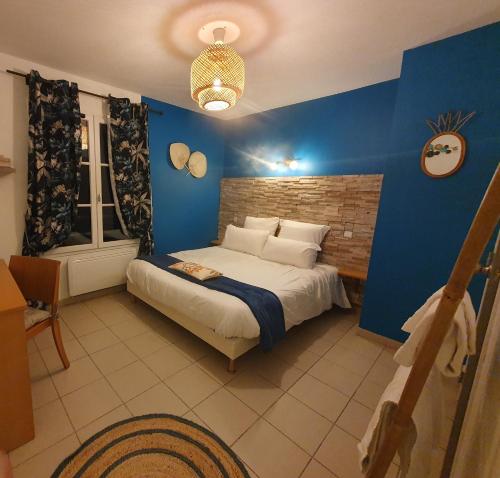 a bedroom with a bed with a blue wall at L EVASION in Cuxac-Cabardès