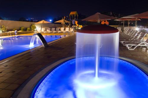 a drink sitting on a table next to a swimming pool at night at Apartamentos Esperanza del Mar in Portonovo