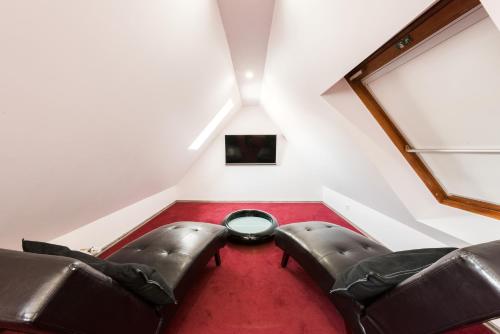 a attic room with two leather chairs and a table at Bürgerhofhotel in Cologne