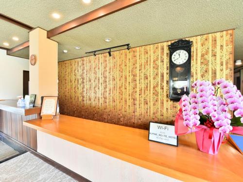 a counter with a clock and flowers on it at Arya Hotel Alpin Route - Vacation STAY 81598v in Omachi