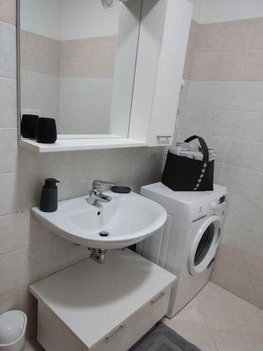 a bathroom with a sink and a washing machine at L&G APARTAMENT in Nago-Torbole