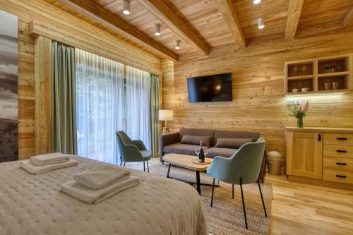 a bedroom with a bed and a couch and a television at KRÁĽOVOHOĽSKÁ CHATA in Šumiac