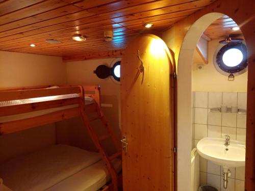 a small room with a bunk bed and a sink at Küstenmotorschiff Aventura in Bremen