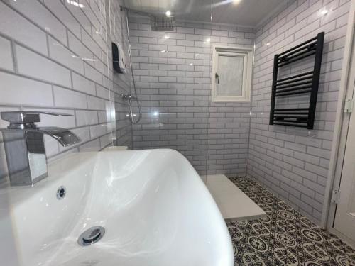 a white bath tub in a white tiled bathroom at Sleeps 10-12 Snowdonia North Wales Nr Zip World in Tanygrisiau