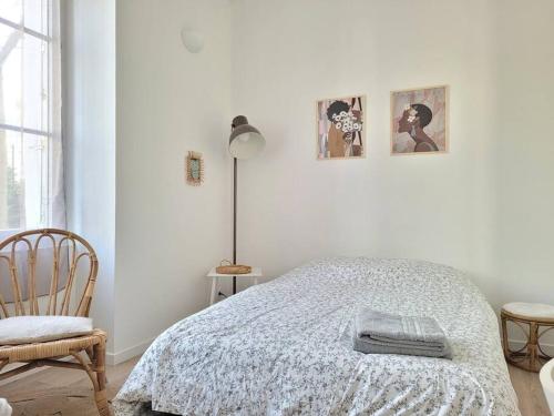 ein weißes Schlafzimmer mit einem Bett und einem Stuhl in der Unterkunft Cocoon Urbain Nantais in Nantes