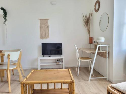 ein Wohnzimmer mit einem Tisch und einem TV in der Unterkunft Cocoon Urbain Nantais in Nantes