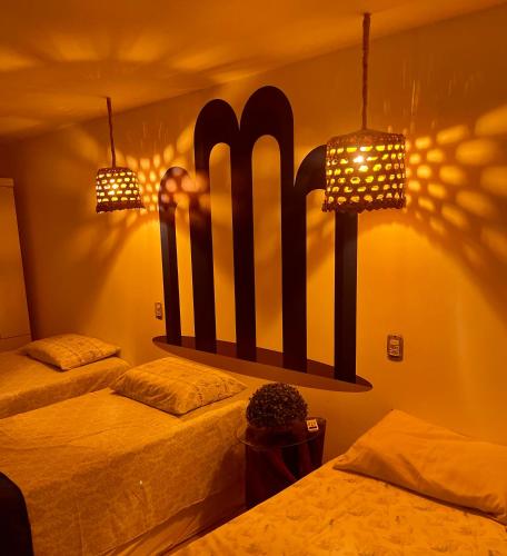 two beds in a room with two lights on the wall at Residencial Temporada Aracaju in Aracaju