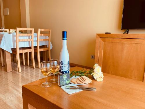 a bottle of wine and two glasses on a table at Apartamentos Esperanza del Mar in Portonovo
