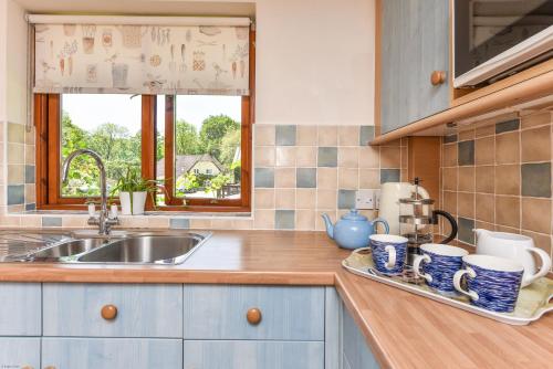 a kitchen counter with a sink and a window at Taylors Copse Cottage by Inspire Stays in Petersfield