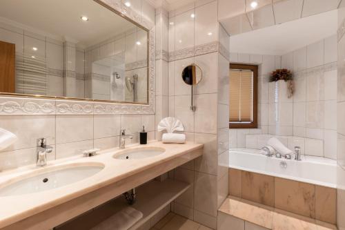 y baño con 2 lavabos, bañera y espejo. en Hotel Schlosshof, en Ischgl