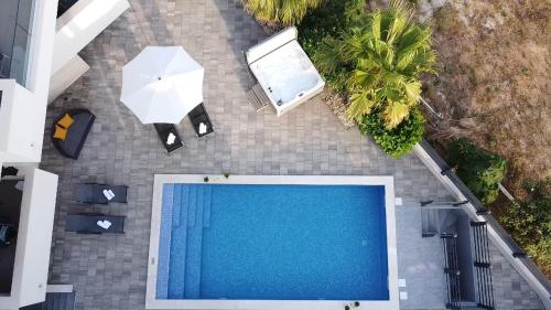 una vista aérea de una piscina y una sombrilla en Apartments Pool Villa Aldura, en Novalja