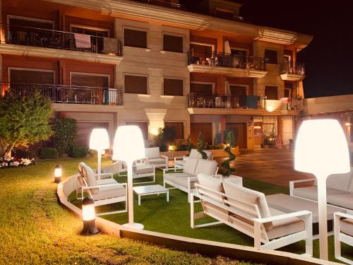 un patio del hotel con sillas blancas y luces en Hostal Esperanza del Mar, en Portonovo